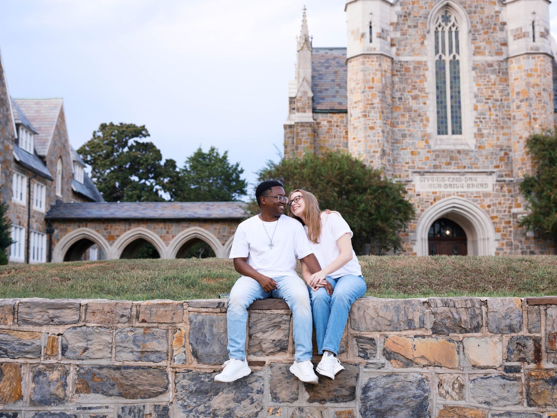 Kendrick and Jensen sitting together on a stone wall in front of the chapel
